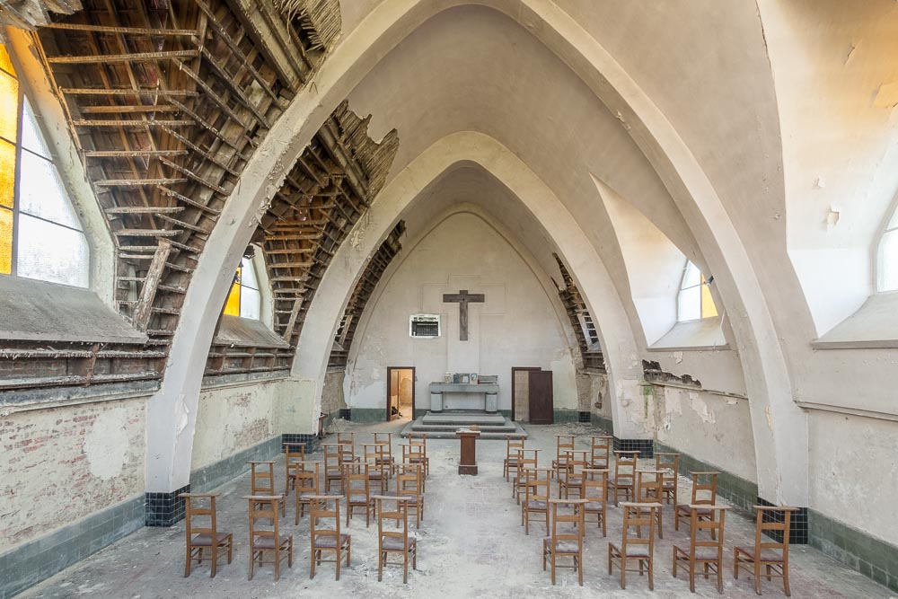 binnenzicht in urbex locatie chapelle des mineurs, van deur
            naar altaar